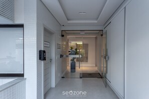 Een moderne hal met een glazen deur, een digitaal slot en een bord dat de locatie aangeeft.