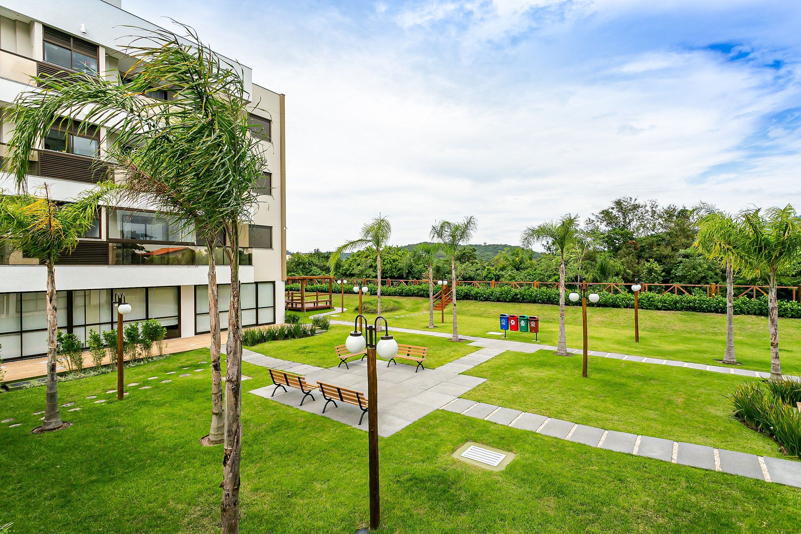 Un edificio moderno con un patio que incluye bancos, un sendero y un césped bien cuidado.