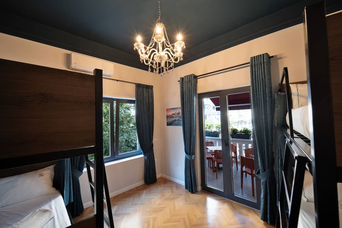 A room with bunk beds, a chandelier, and a view of the outdoors.