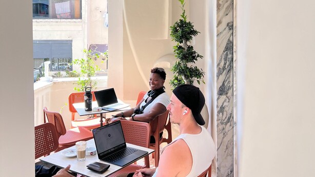 An outdoor seating area with tables and chairs, a potted plant, and a unique architectural feature. - 2115 Boutique Hostel (Durrës)