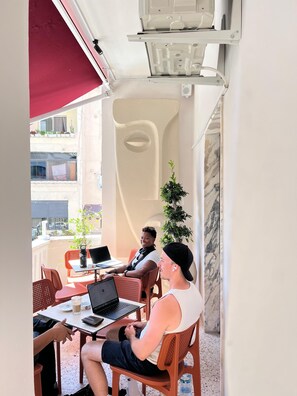 An outdoor seating area with tables and chairs, a potted plant, and a unique architectural feature. - 2115 Boutique Hostel (Durrës)