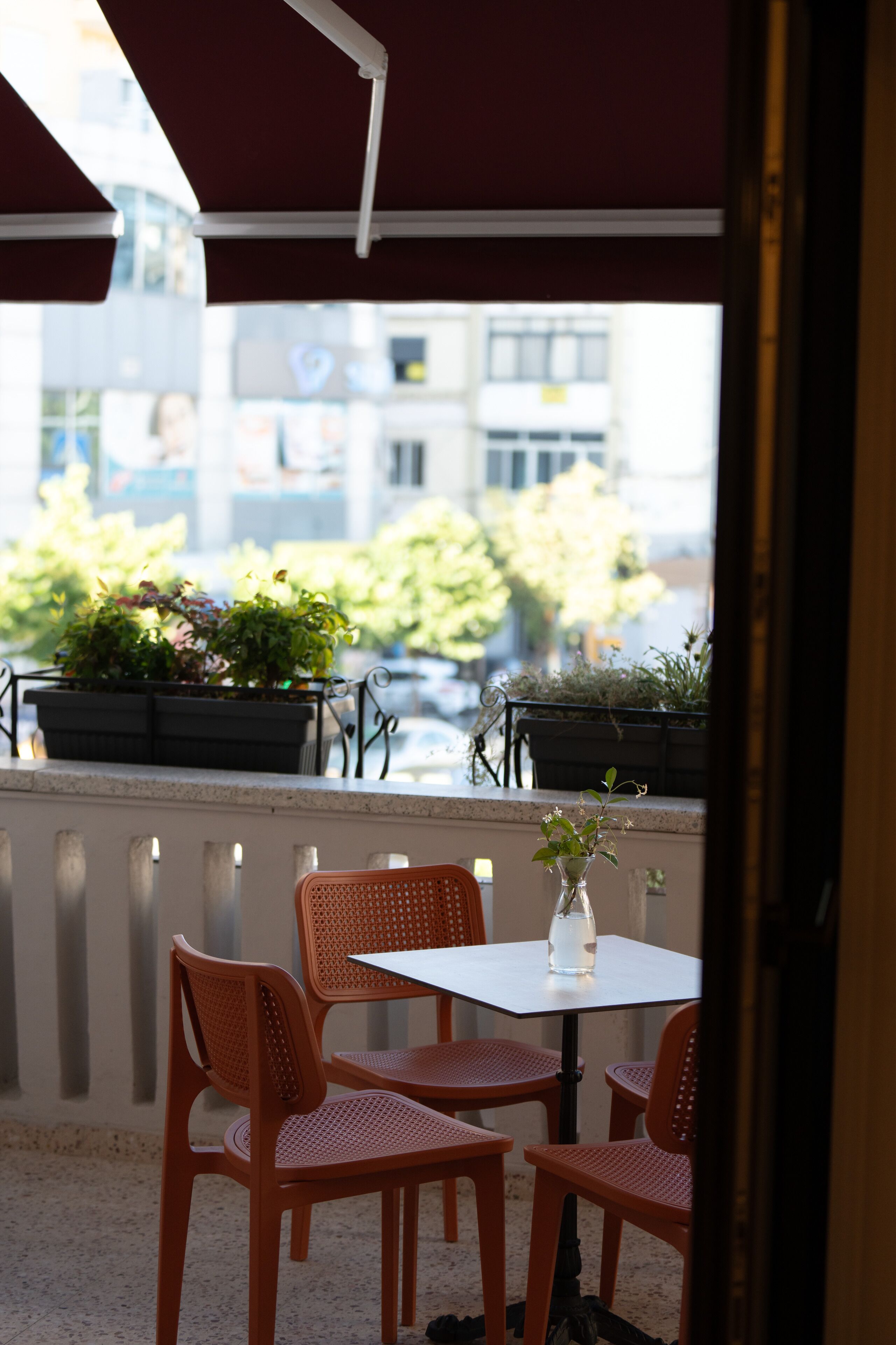 An outdoor seating area with a table and chairs, potted plants, and a view of the cityscape.