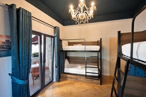 A room with bunk beds, a chandelier, and a sliding glass door leading to an outdoor area. - 2115 Boutique Hostel (Durrës)