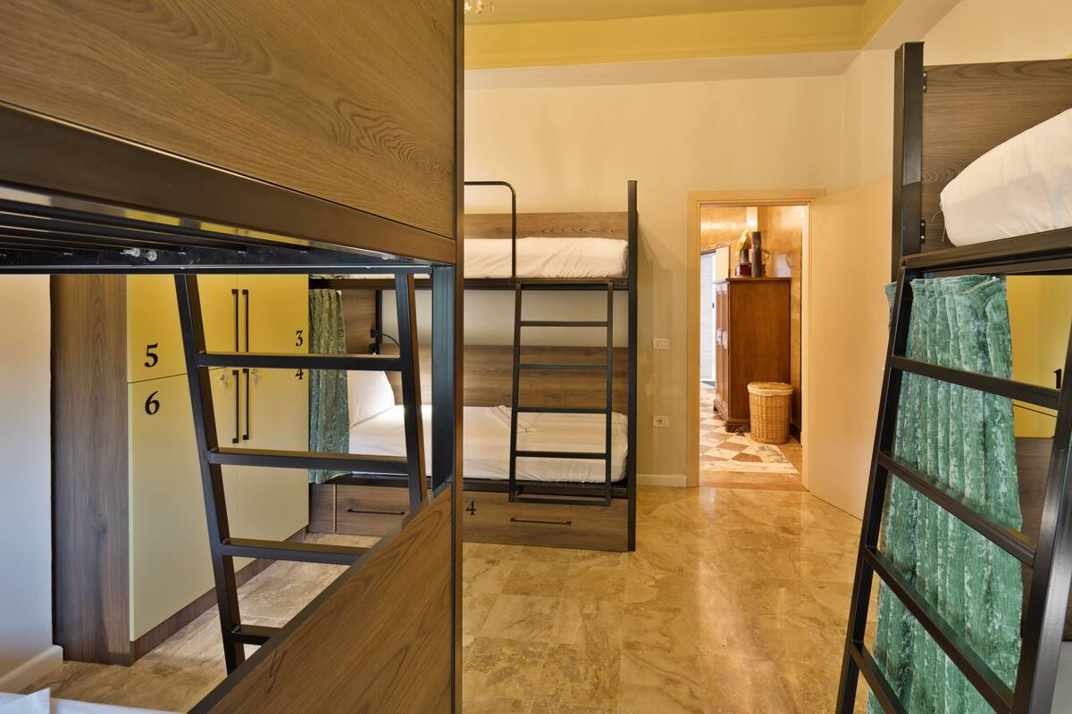 A dormitory room with bunk beds, wooden walls, and a tiled floor.