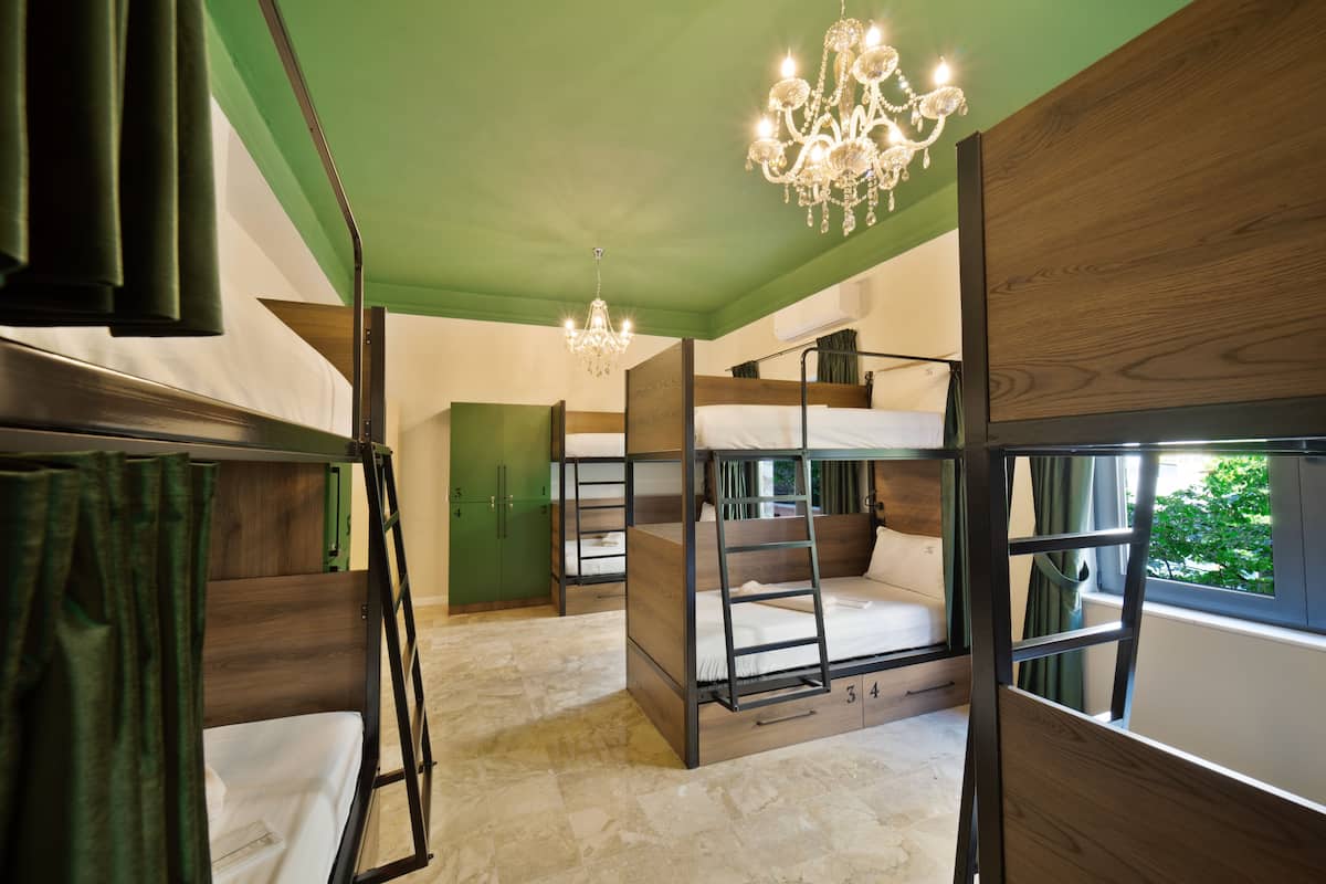 A bunk bed room with a chandelier, a window with a view, and a green wall.