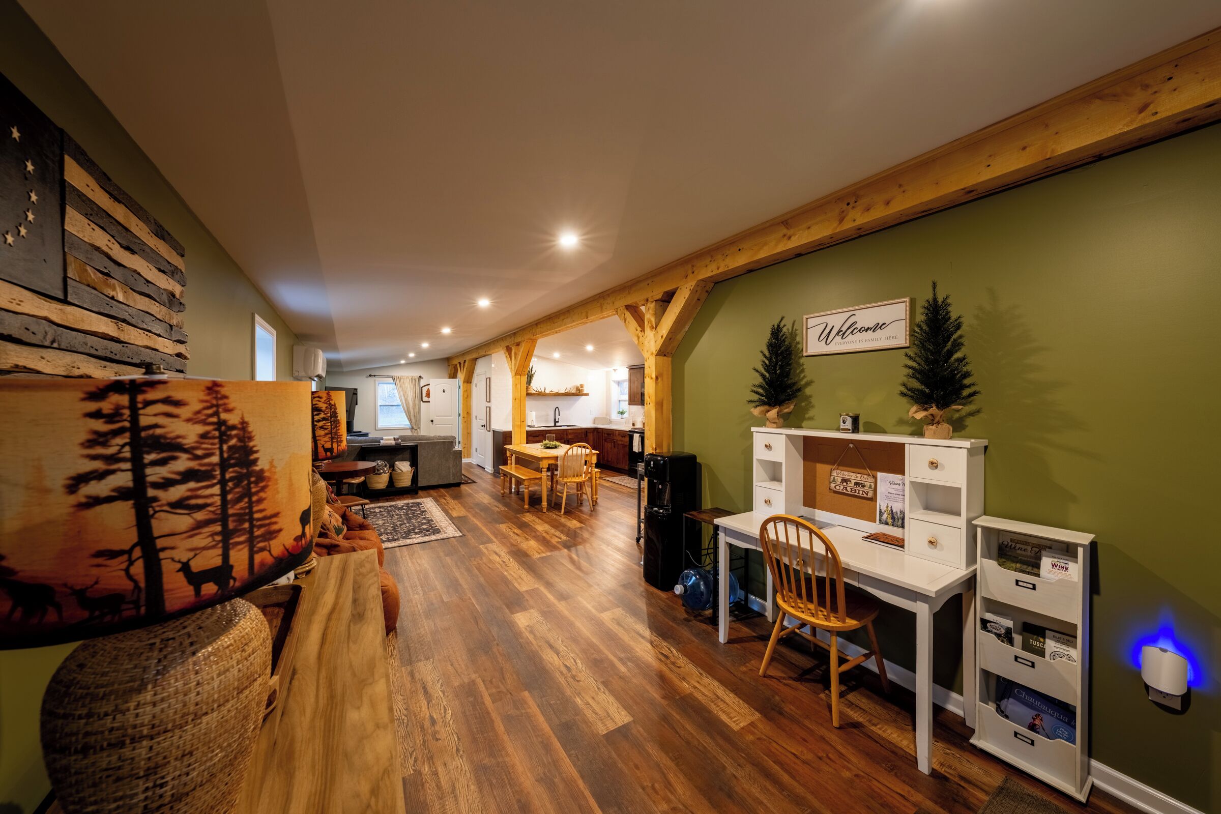 A spacious room with a wooden floor, a desk, a chair, a bookshelf, and a wall-mounted sign.