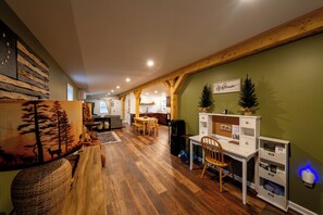 A spacious room with a wooden floor, a desk, a chair, a bookshelf, and a wall-mounted sign. - Cozy Fall Getaway- 35 Min to Bills Stadium- Wineries + Trails (Silver Creek)