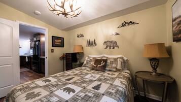 A bedroom with a large bed, a chandelier, a wall with animal decals, and a door leading to a kitchen.