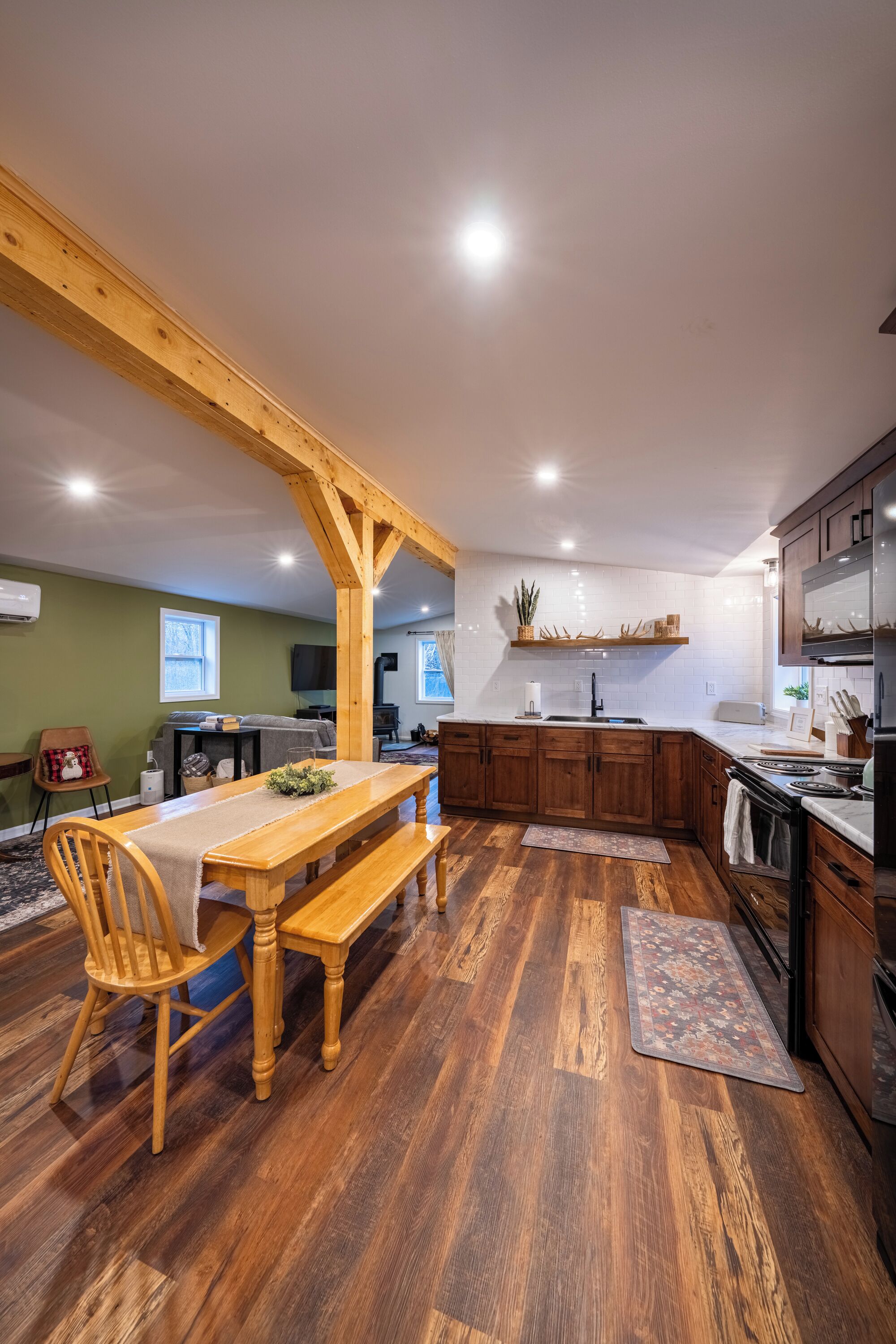 A spacious kitchen with wooden beams, a dining area with a bench, and a large window.