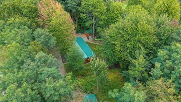 Un chalet isolé, entouré d’une forêt dense, avec un sentier bien tracé menant à l’entrée.