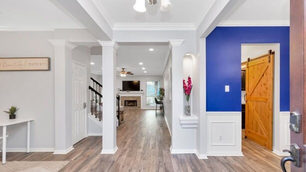 A spacious hallway with wooden flooring, white walls, and a blue accent wall. - Hickory Trl King Bed w/ Pool | Near Jersey Village (Houston)