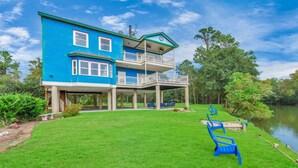 A two-story house with a balcony, a grassy yard, and a lake view.