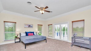 A bedroom with a bed, a ceiling fan, and a crib.