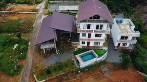 Un edificio residenziale a più piani con piscina, immerso nel verde e con un sentiero sterrato.