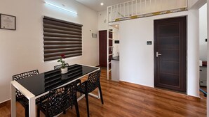 Un'area pranzo con un tavolo e sedie neri, una ventola a soffitto e una finestra con persiane.