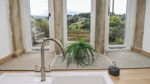 A bathroom with a large window, a sink, and a plant. - Hill Top Cottage (Holmfirth)