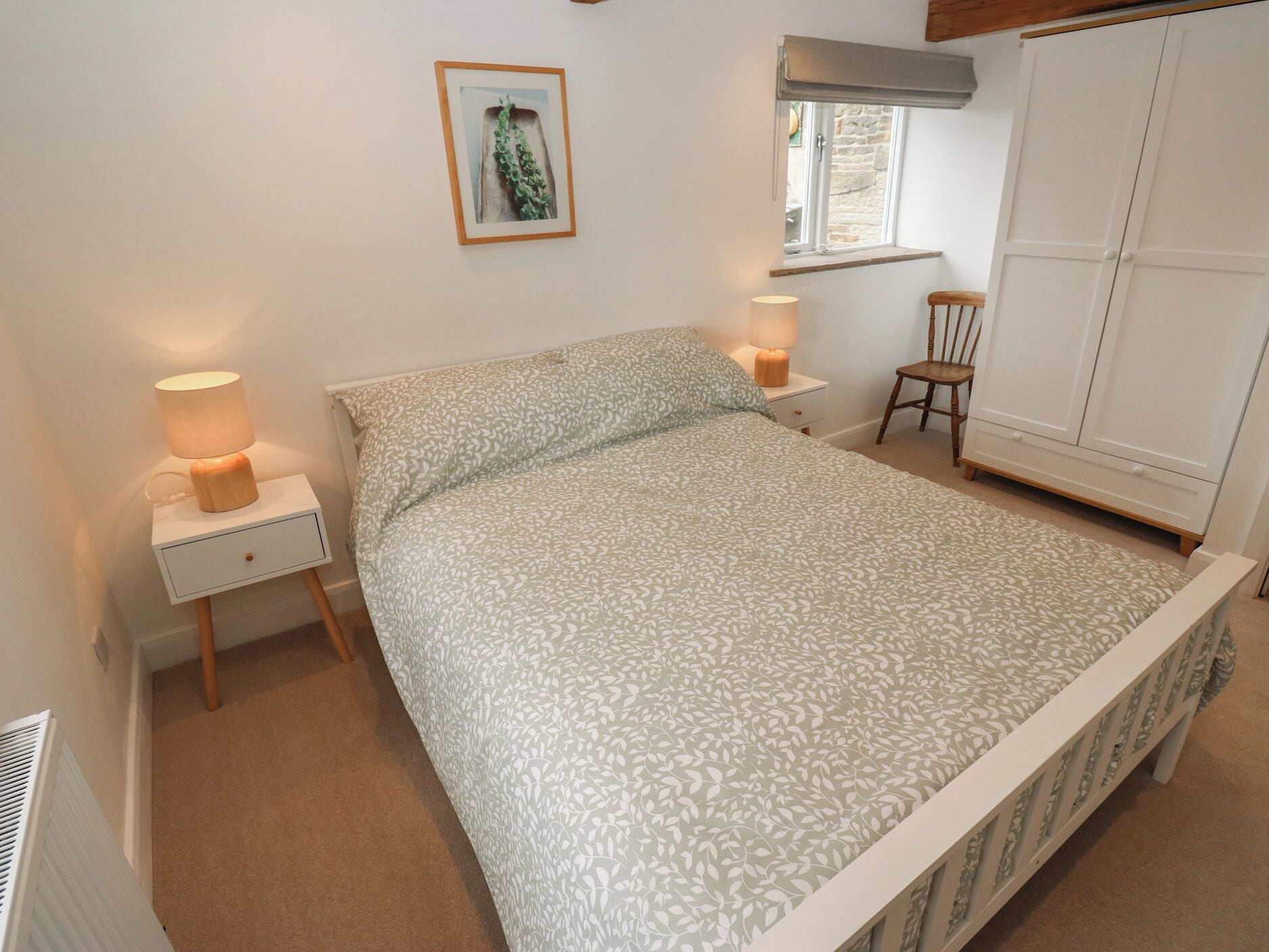 A bedroom with a bed, bedside tables, a chair, a wardrobe, and a window.