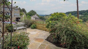 A stone pathway leading to a wooden bench, surrounded by lush greenery and a stone wall. - Hill Top Cottage (Holmfirth)