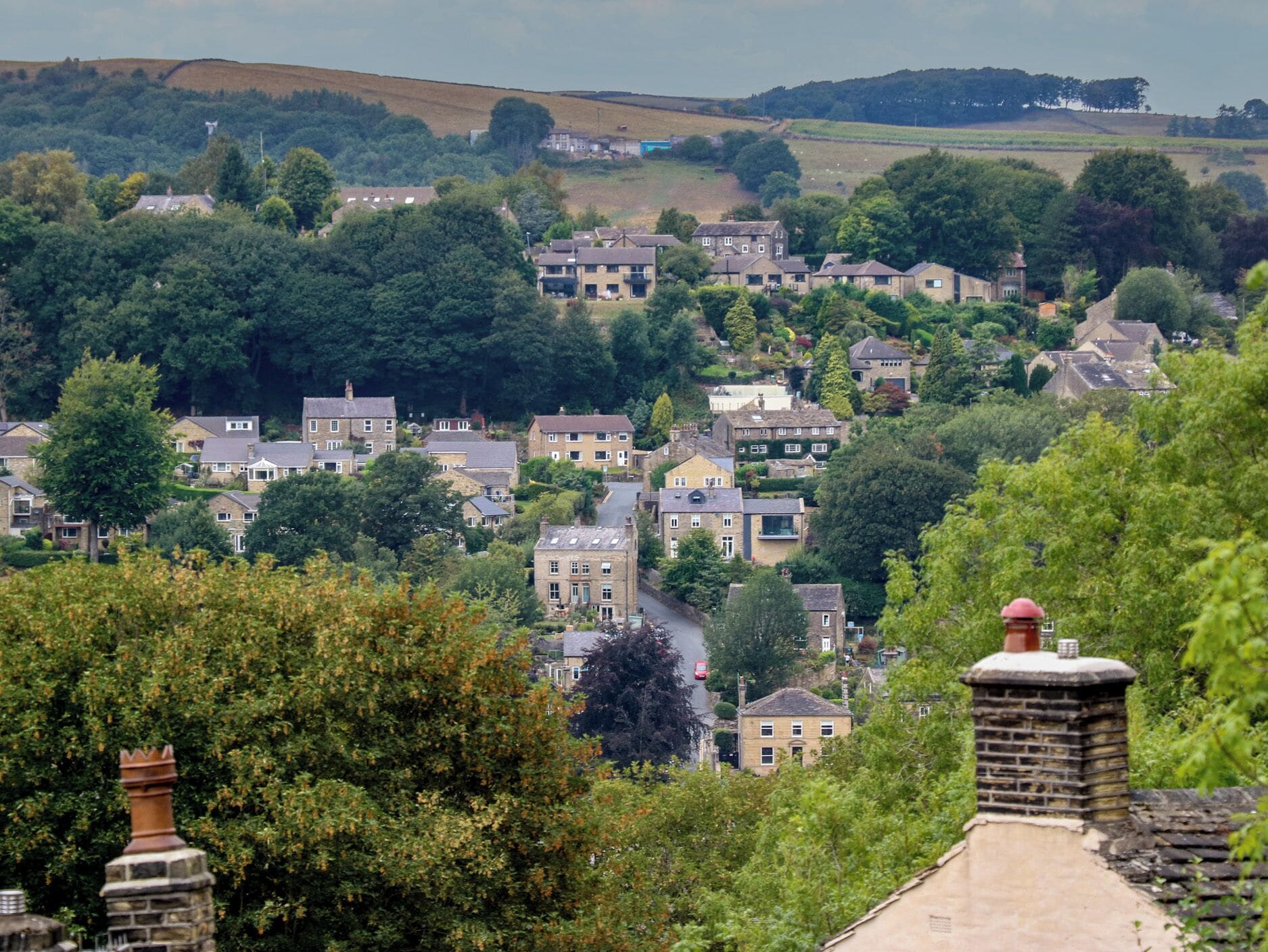 A village with traditional houses, a main road, and surrounding greenery.