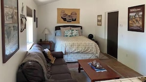 Un dormitorio con cama, sofá, mesita de noche, lámpara y un póster en la pared.