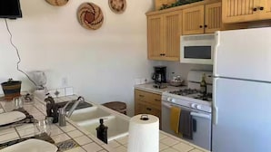 Una cocina con armarios de madera, estufa, refrigerador y pileta.