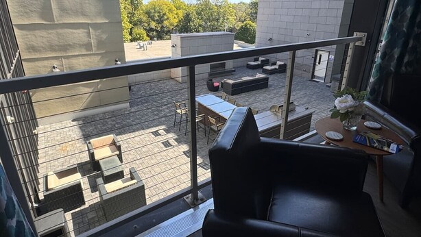 Een balkon met uitzicht op een terras op een dak, inclusief zitplaatsen buiten en een tafel met een bloevas.