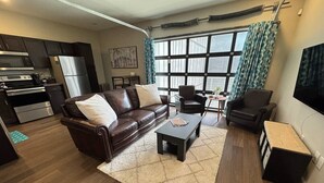Een moderne woonkamer met een bruine leren bank, een bijzettafeltje en een televisie.