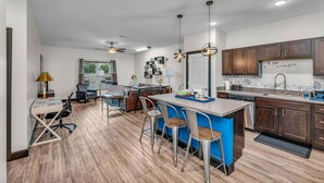 A modern kitchen with a central island, bar stools, and a dining area. - Loft 207- Modern Condo with Rooftop Terrace Access (Lawrence)