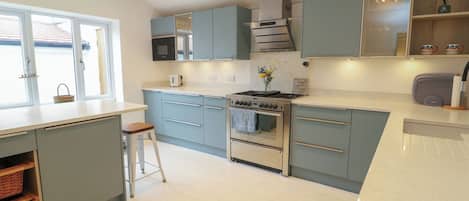 A modern kitchen with light blue cabinets, a stainless steel stove, and a large window.