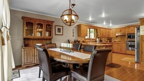 A spacious kitchen with wooden cabinets, a central island, and modern appliances. - Secluded EVL Getaway with Hot tub, Sauna, Fire Pit, Gym & Game room (Ellicottville)
