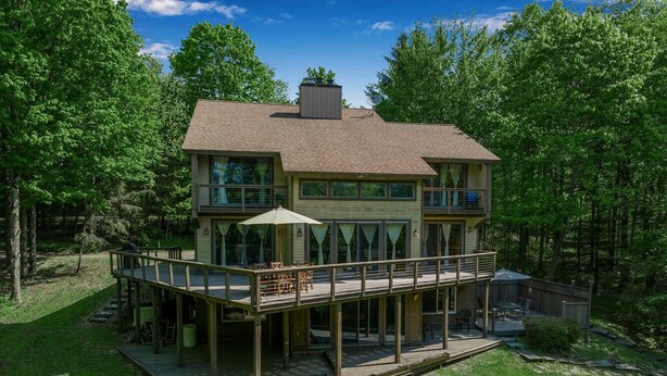 A two-story house with a deck and outdoor seating area. - Secluded EVL Getaway with Hot tub, Sauna, Fire Pit, Gym & Game room (Ellicottville)