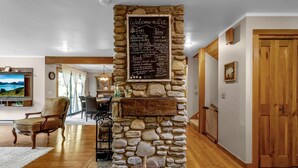 A stone fireplace with a chalkboard listing amenities like ski, spa, and food options. - Secluded EVL Getaway with Hot tub, Sauna, Fire Pit, Gym & Game room (Ellicottville)