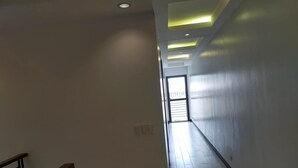 Un passadís amb una escala de fusta a l'esquerra, una barana negra i una porta que dóna a un balcó.