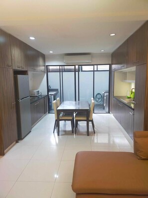 Una cocina moderna con comedor, que incluye una mesa grande, sillas, un refrigerador y un microondas.