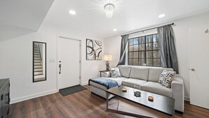 A modern living room with a grey sofa, a coffee table, and a staircase. - Secluded PoolHouse Estate (College Park)
