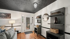 A modern living room with a grey sofa, a chandelier, and a wooden floor. - Secluded PoolHouse Estate (College Park)