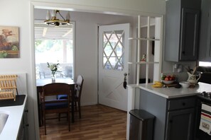 A kitchen with a dining area, wooden flooring, and a window with blinds.