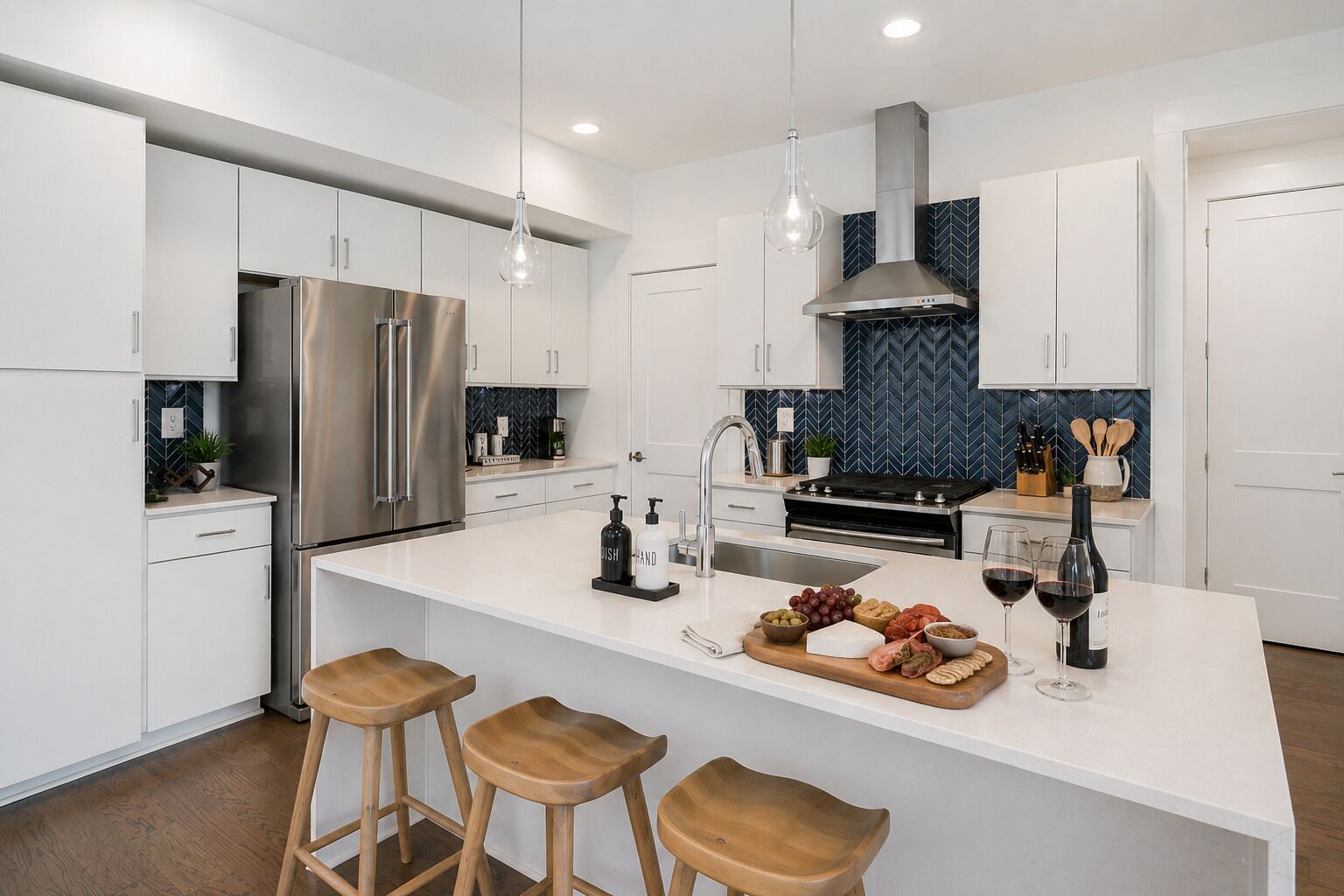Cozinha moderna com armários brancos, eletrodomésticos de aço inoxidável, uma ilha central com banquetas e um backsplash azul em padrão herringbone.