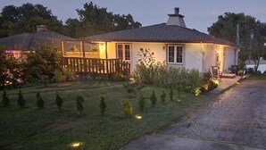 Una casa con un prato curato, un patio in legno e un portico con posti a sedere esterni.