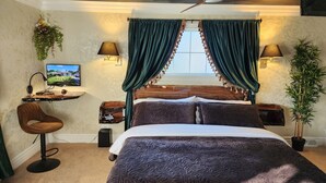 Una camera da letto con un letto, una scrivania, una sedia, una televisione e una ventola a soffitto.