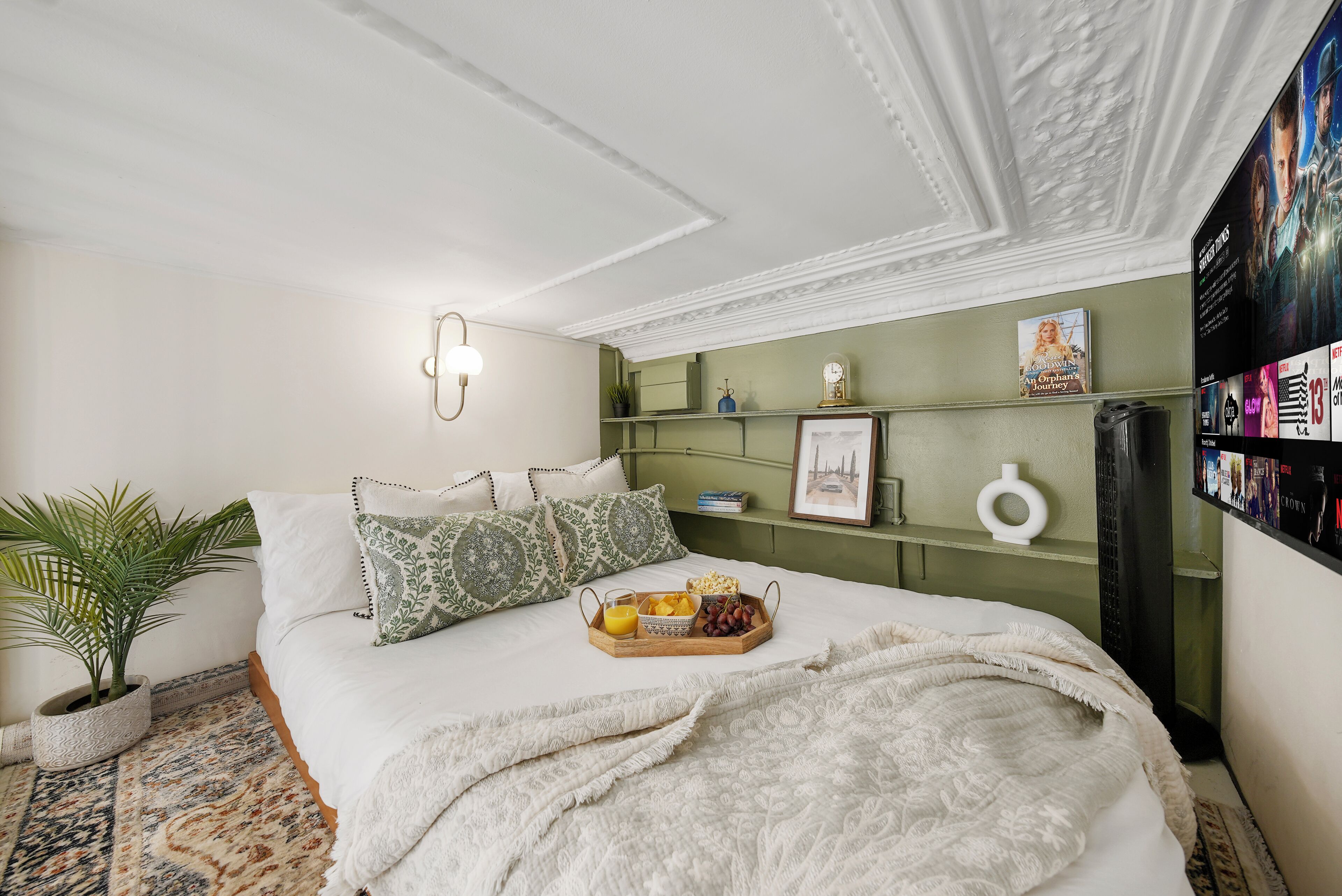 A neatly arranged bedroom with a bed, bedside table, and a wall-mounted TV.