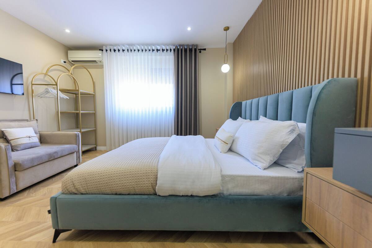 A modern bedroom with a bed, a sofa, a wardrobe, and a TV.