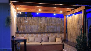 A cozy seating area with a cushioned bench, a small table, and a decorative bamboo wall. - Syncron Rooftop City Centre Tirana (Tirana)
