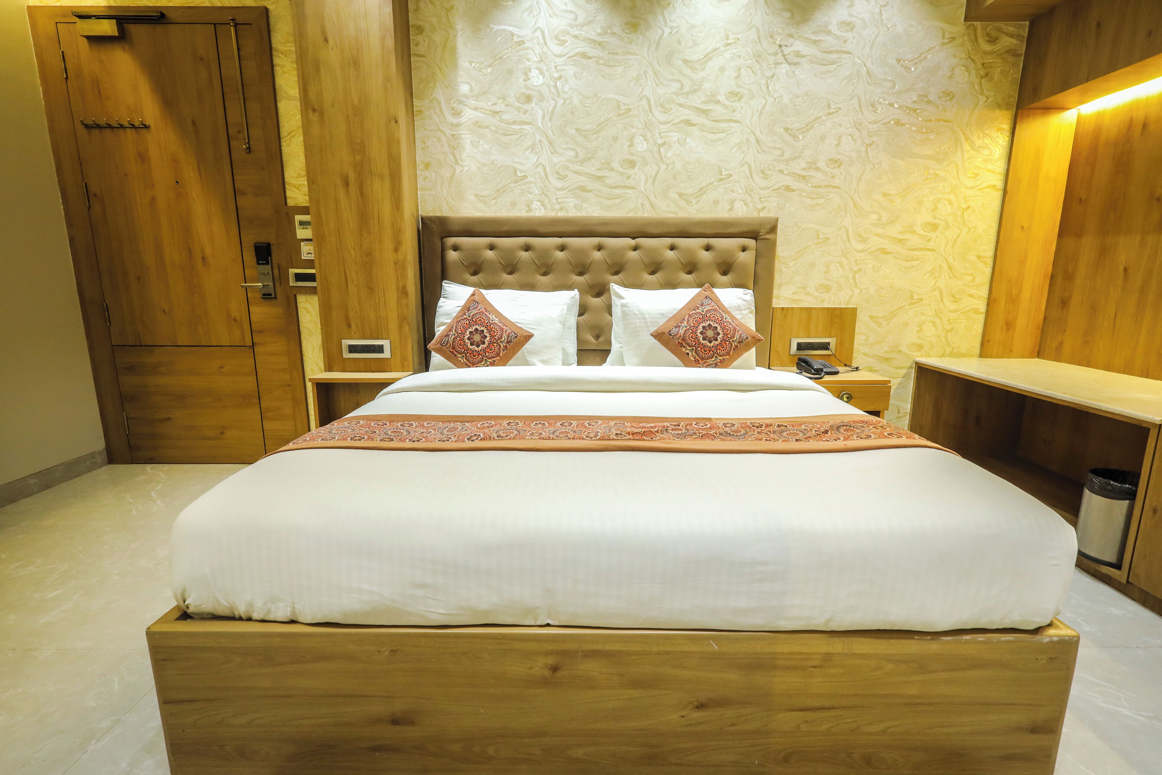 Un letto in legno con testiera imbottita, due comodini e un tavolino da notte.