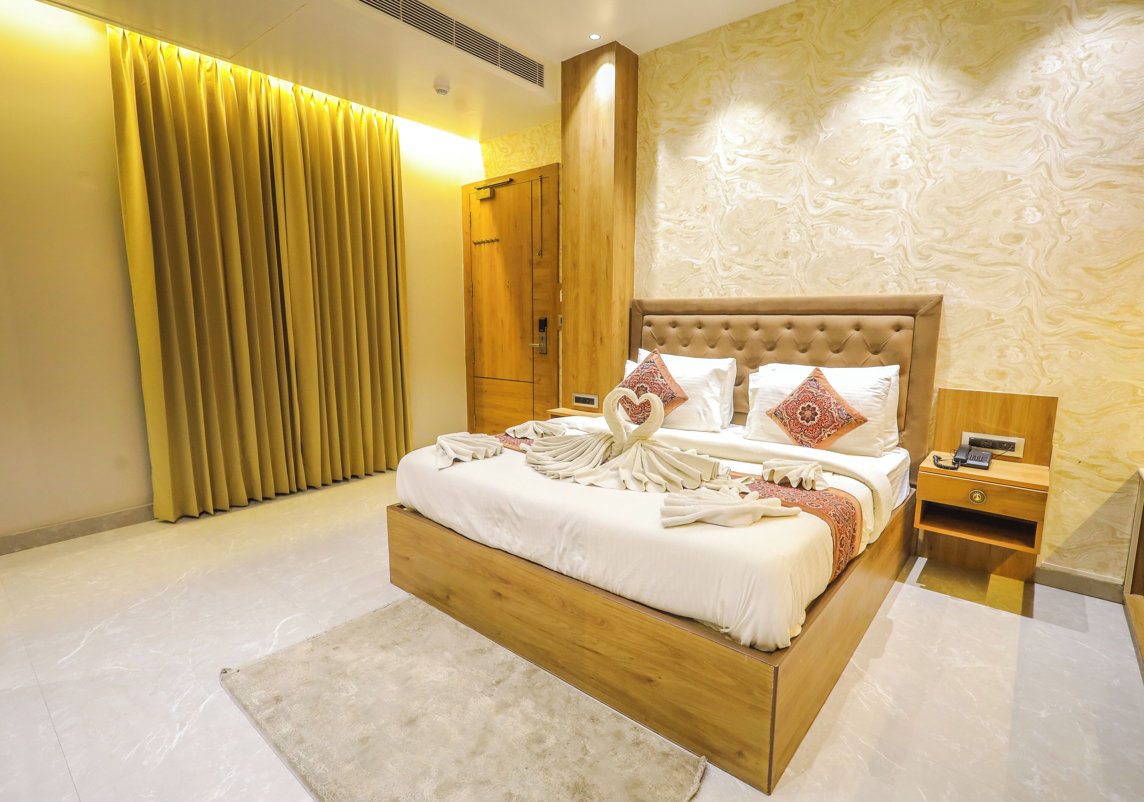Um quarto espaçoso com uma cama grande, cabeceira de madeira e uma mesinha de cabeceira.