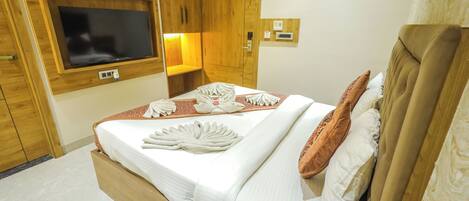 Una habitación de hotel con una cama de madera, un televisor montado en la pared y un armario de madera.