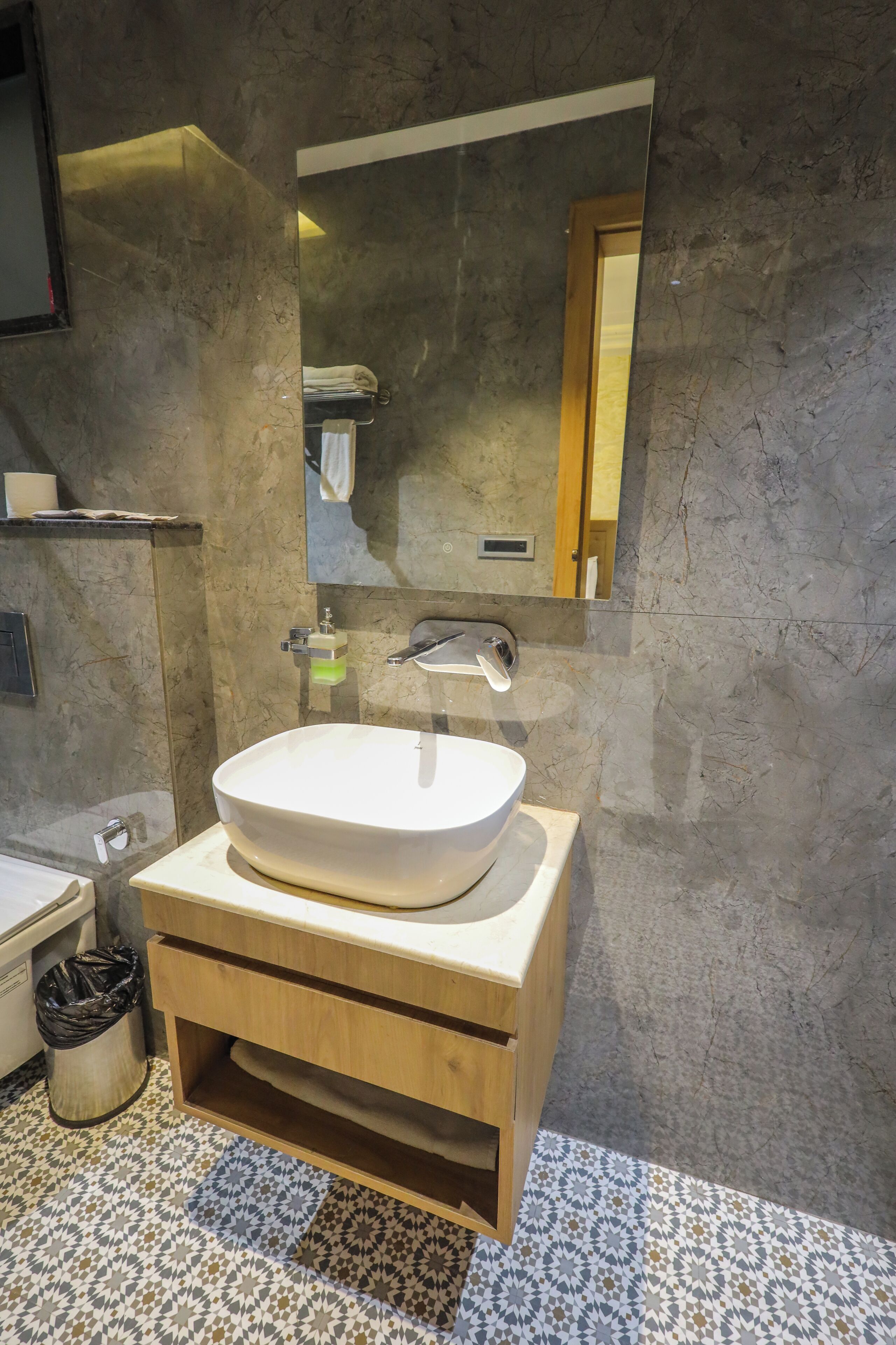 A bathroom with a marble sink, wooden vanity, and a mirror.