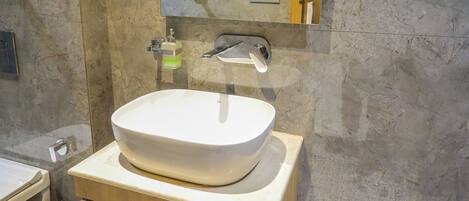 A bathroom with a marble sink, wooden vanity, and a mirror.