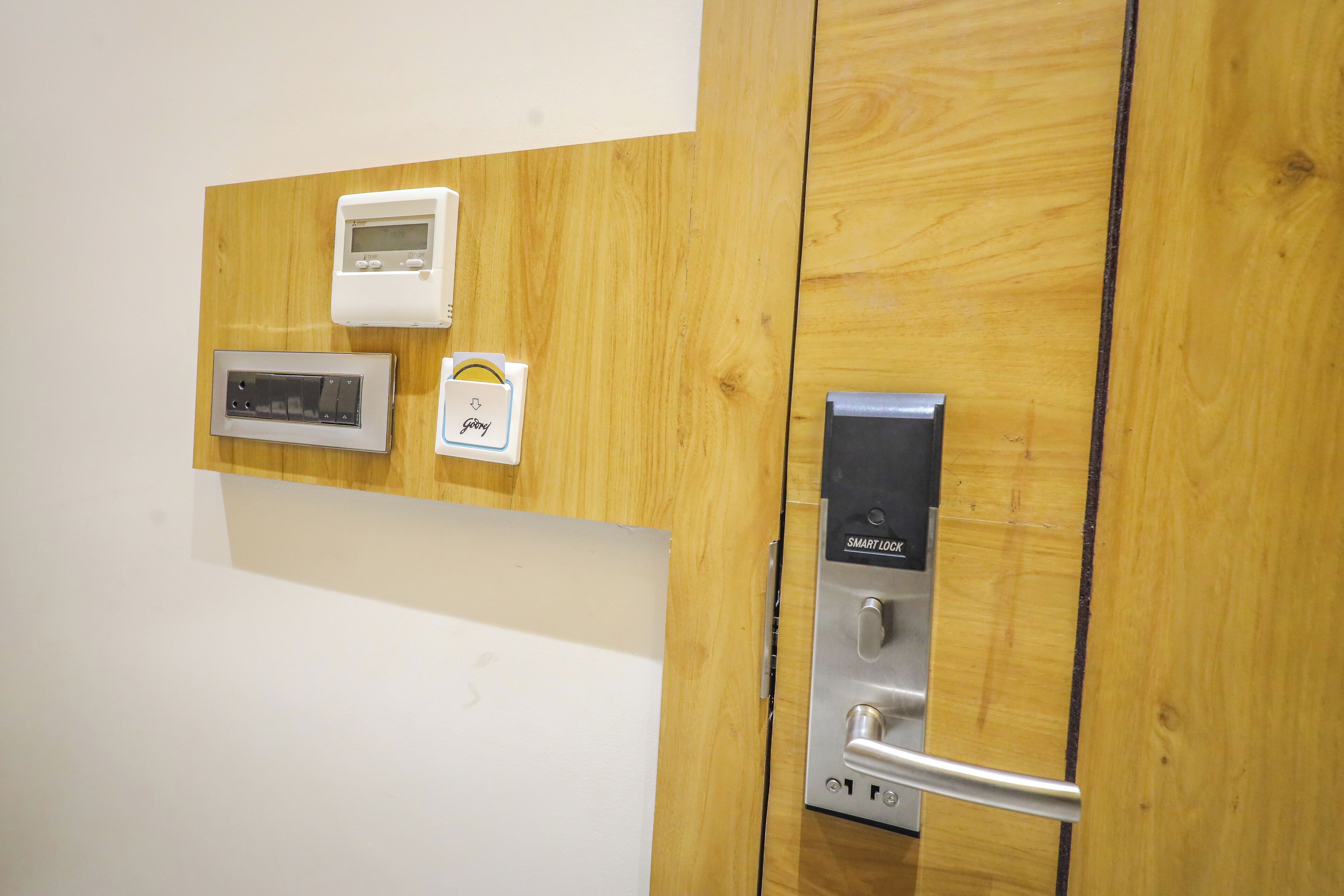 A wooden door with a built-in control panel featuring a digital thermostat, a microwave, and a smart lock.