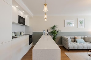 Een moderne keuken met een centraal eiland, een inbouwmagnetron en een hanglamp.